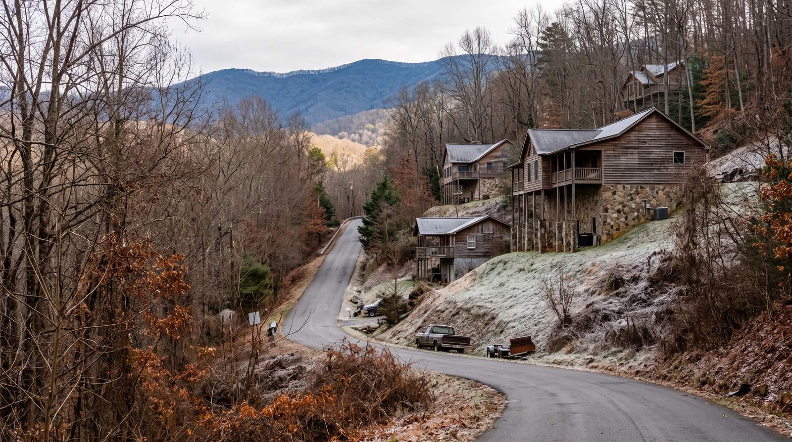 Houses stepped up a steep wooded slope below a blue ridge, with hard frost still lying in the shaded ground.